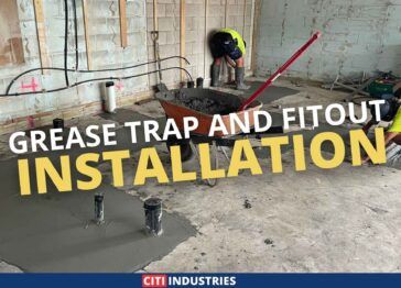 Team of plumbers finishing concrete above grease trap lines with text overlay: 