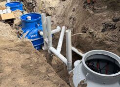 Underground installation of a grease trap system with vent and outlet connections.