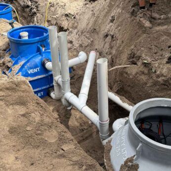 Underground installation of a grease trap system with vent and outlet connections.