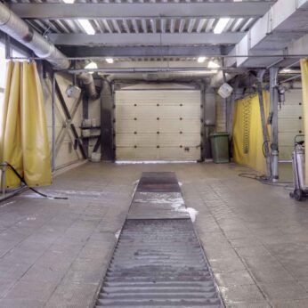 Interior view of a modular wash bay installation with yellow curtains and cleaning equipment.