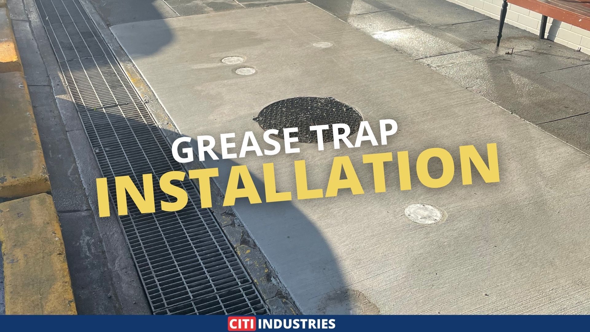 Concrete walkway with drainage grate and manhole covers above a completed grease trap Acacia Ridge installation